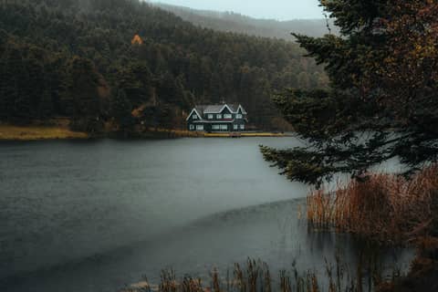 Charming lake house surrounded by autumn foliage in Bolu, Turkey, capturing serene natural beauty.