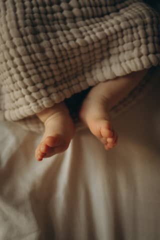 A baby wrapped in a blanket on top of a bed