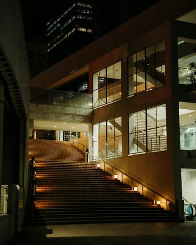 Illuminated modern staircase at night in an urban cityscape, showcasing architectural symmetry.