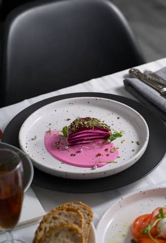 A gourmet beet dish elegantly plated with vibrant pink sauce and garnishes, ideal for culinary presentations.