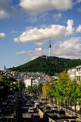 Bright cityscape of Seoul featuring the iconic Namsan Tower on a clear day with bustling streets below.