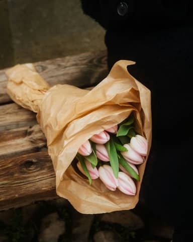 A bouquet of tulips wrapped in brown paper.