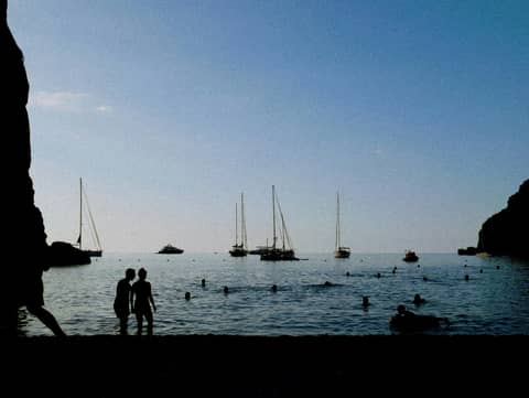 A couple of people standing next to a body of water