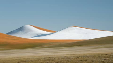 Snowy hills sit in a yellow landscape.