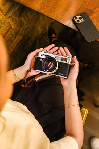 Person holding vintage camera, capturing creative moments indoors.