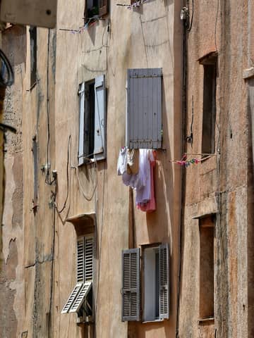 Weathered Mediterranean building facade with colorful laundry hung out to dry.