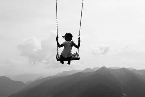 Silhouette of a woman swinging high above the mountains in Vipiteno, Italy, capturing a sense of freedom and adventure.