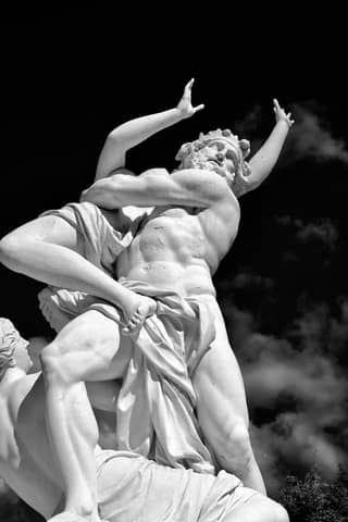 Dynamic white marble sculpture against a dramatic clouded sky.