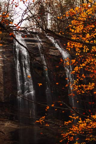 A serene view of a waterfall framed by vibrant autumn leaves in Bursa, Türkiye.