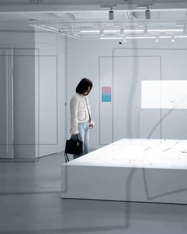 A woman in a white room looking at a painting