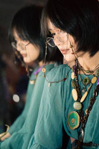 Artistic portrait of a woman wearing vintage jewelry while gazing into a mirror, creating a reflection.