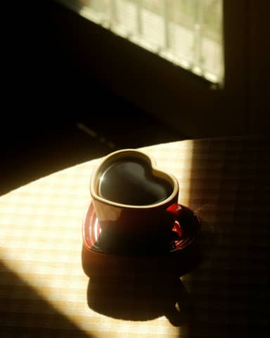 Heart-shaped coffee cup in warm sunlight.