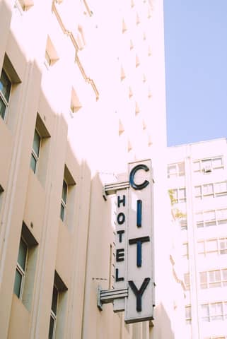 Elegant vintage hotel sign in city scene, bathed in warm sunlight, showcasing urban architecture.