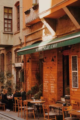 Charming outdoor cafe with patrons enjoying a warm day in a historic alleyway.