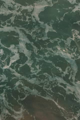 Foamy ocean water swirls around, up close.