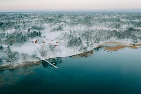 A large body of water surrounded by snow covered trees