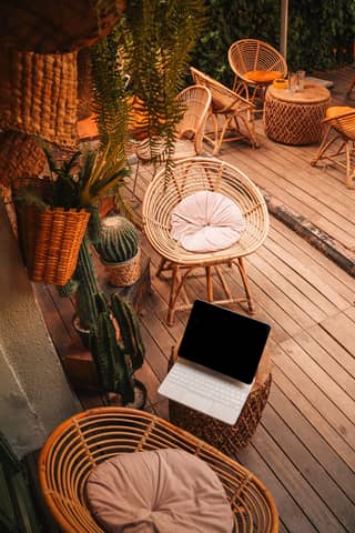 Inviting outdoor space with bamboo furniture and a laptop suggesting a remote work setup.