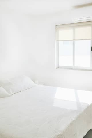 A clean, white bedroom with bright sunlight.