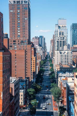 Aerial view of a bustling street in Midtown Manhattan showcasing tall buildings and clear blue skies.