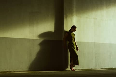 A woman walking down a street next to a wall