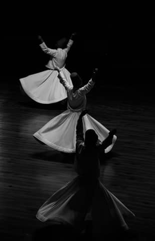 Black and white photo of Sufi whirling dervishes in Konya, embodying spirituality and tradition.