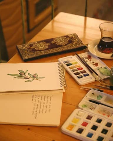 A cozy artist's desk featuring watercolors, sketches, and a warm cup of tea for creative inspiration.
