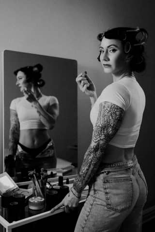 A woman standing in front of a mirror brushing her teeth