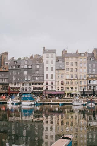 Scenic view of Honfleur's historic harborfront with colorful heritage buildings reflecting on the water.