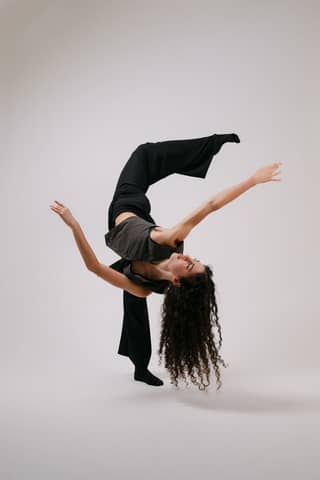 A modern dancer elegantly balancing with arms extended, showcasing flexibility and grace.