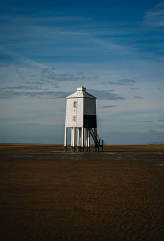 A lighthouse stands on a sandy beach.