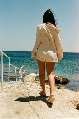 A woman walking down a beach next to the ocean