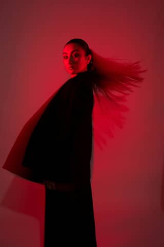 Woman in black, lit dramatically with red light.