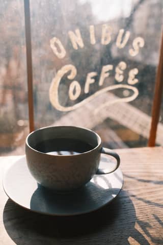 Warm sunlight illuminating a coffee cup in ONIBUS Cafe, Tokyo.
