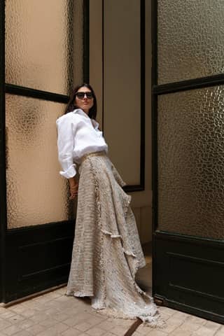 Stylish woman in long skirt and blouse standing by vintage doors.