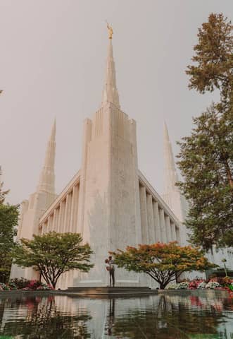 Capture of the stunning Portland Oregon Temple surrounded by lush greenery and reflective pool.