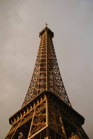 The eiffel tower reaches high into the cloudy sky.