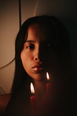 A dramatic portrait of a woman illuminated by candlelight, creating a mysterious ambiance.