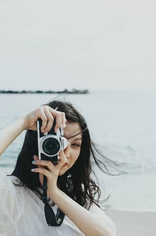 A young woman captures the beauty of the Japanese seaside with her camera.