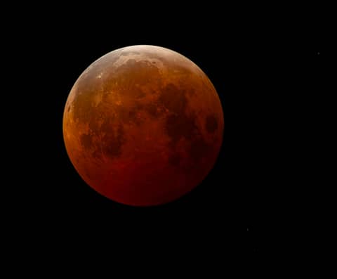 A blood moon is visible in the night sky.