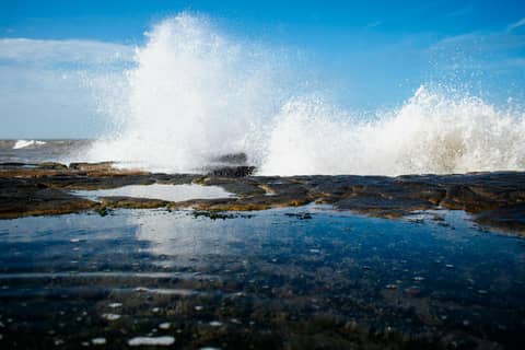 Powerful ocean waves crash against rocky shoreline in Mar del Plata, Argentina.