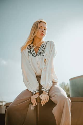 Elegant woman in bohemian attire posing outdoors under a clear sky.