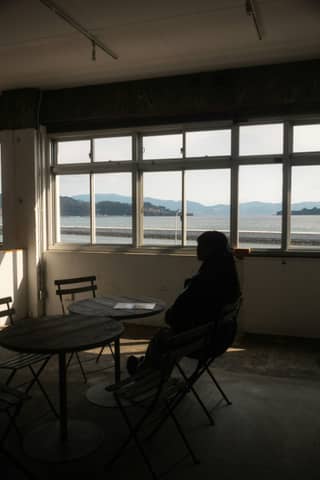 Person sits by the window looking at a scenic view.