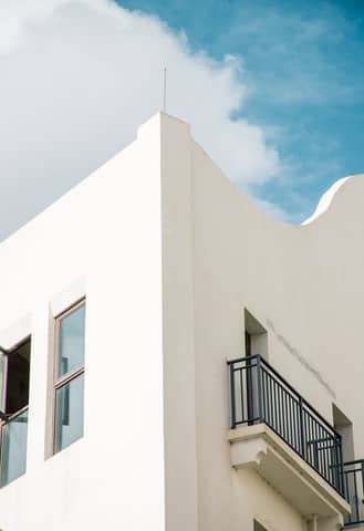 Elegant white building with a balcony, set against a vibrant blue sky.