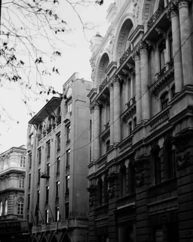Black and white photo of a neoclassical building facade in a city setting.