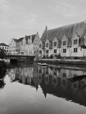 Scenic view of historical buildings and canal in Ghent, Belgium, in moody black and white.