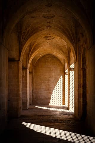 Historic stone corridor in Mardin, Türkiye with dramatic light and shadows.