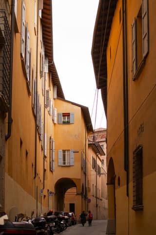 Explore the picturesque narrow streets of Bologna with its iconic warm-toned buildings and classic architecture.