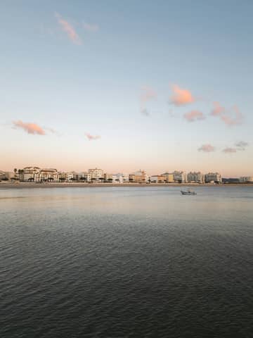 City skyline meets the sea under a calm sky.