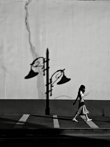 Artistic black and white photo capturing a silhouette walking by a streetlamp shadow in Istanbul, Türkiye.