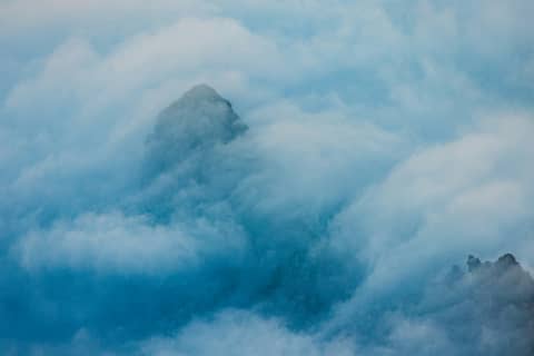 Mountains are shrouded in thick, blue clouds.